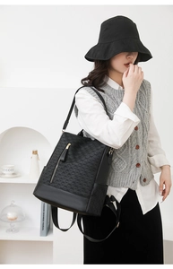 Close-up of black anti-theft backpack featuring geometric interlocking patterns and gold zippers