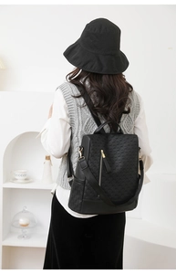 Close-up of black anti-theft backpack featuring embossed grid texture and gold zipper