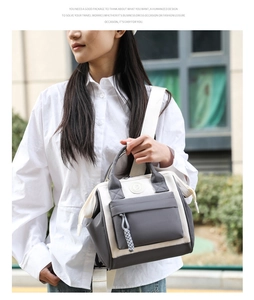 Detalle de bolsa de pañales de nailon beige y gris con correa tejida en un entorno callejero