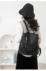 Detail view of the black backpack featuring geometric embossed texture and vertical zipper