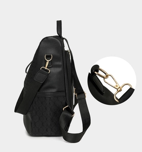 Detail of black anti-theft backpack showing gold metal hooks and geometric textured fabric