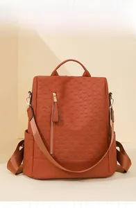 Close-up of orange faux leather backpack showing woven texture and gold zipper detail
