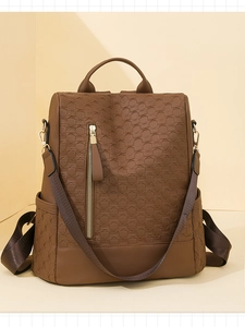 Detail of brown faux leather backpack with 3D hexagonal texture and gold vertical zipper