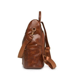 Detail view of brown PU leather backpack showing side pocket and golden metal hook
