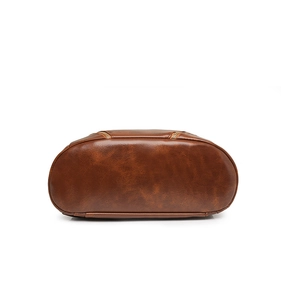 Detail view of the reinforced bottom stitching and gold zippers on the brown PU leather backpack