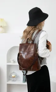 Brown PU leather backpack detail showing anti-theft design on a model back view
