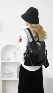 Close-up of minimalist black PU leather backpack featuring premium golden zippers and texture