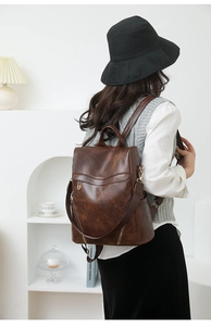 Detail of dark brown faux leather backpack featuring a vintage finish and gold hardware