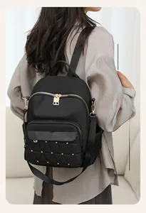 Detail view of black oxford backpack featuring quilted texture and gold rivet accents
