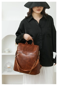 Detail of vintage brown PU leather backpack featuring textured finish and wide fabric strap