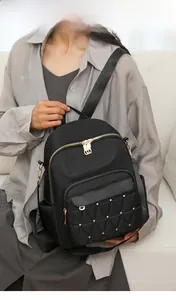 Detail of black oxford backpack featuring quilted diamond pattern and gold stud accents