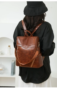 Detail of dark brown vintage PU leather backpack with rich texture and metal zippers