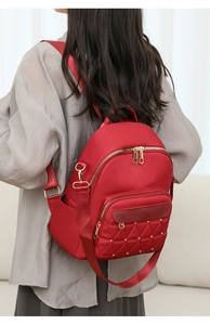 Detail of red quilted oxford backpack with golden rivets and dual zippers