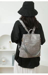 Detail of dark gray PU leather backpack showing vintage texture and golden metal pin hardware