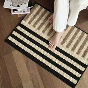 Nordic striped non-slip bath mat in black, beige, and brown on a wooden floor