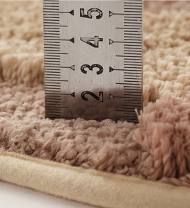 Close-up showing the 3cm thick plush pile height of the Nordic moss rug using a ruler