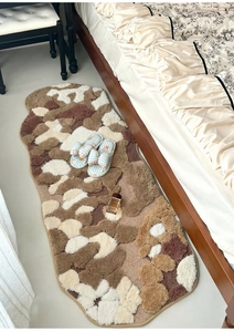 Close-up of irregular moss-style bedside rug with high-low tufted pile and earthy tones