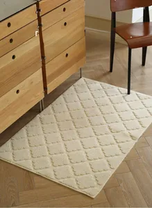 Detail of cream woven door mat with diamond texture on herringbone wooden floor