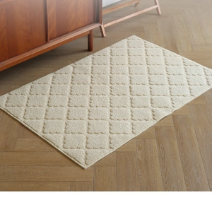 Detail of cream entry mat with diamond pattern on light wood herringbone floor