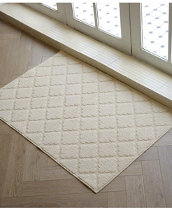Detail view of cream tufted doormat with rhombus texture on elegant wooden floor
