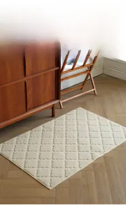 Close-up of cream textured rug with raised diamond pattern on wood herringbone floor