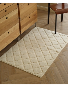 Close-up of beige cream rug with 3D diamond texture on a wooden herringbone floor