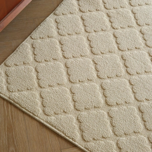 Creamy thick entrance mat with 3D checkered texture and wavy edges on wooden floor