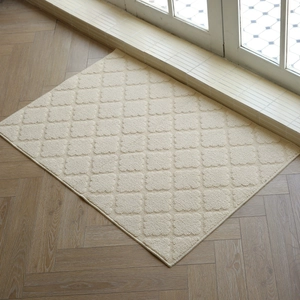 Cream rectangular tufted entryway mat with diamond pattern on wooden floor