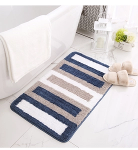 Detail of plush striped bathroom mat with thick absorbent fibers by a white bathtub