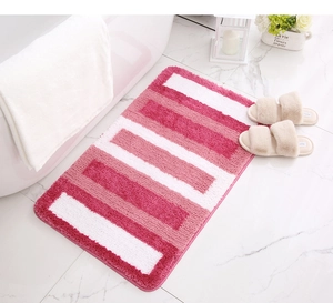Detail view of pink and white striped plush bath mat on white marble floor