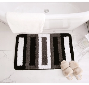 Close-up of fluffy striped bathroom rug with non-slip texture near white marble bathtub