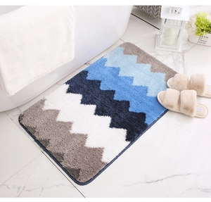 Détail du tapis de bain moelleux à vagues bleues placé à côté d'une baignoire blanche