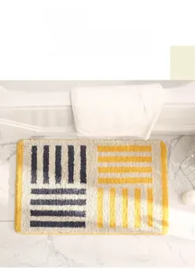 Vue détaillée du tapis de bain géométrique avec flocage doux et bordure jaune serrée