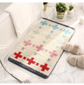 Détail d'un tapis de bain doux antidérapant avec motifs de croix colorés sur sol marbre