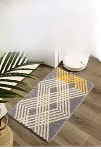 Détail du tapis de bain géométrique gris et jaune sur parquet avec robot aspirateur