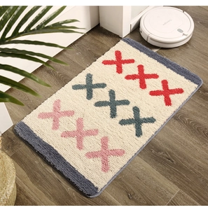 Gros plan d'un tapis de bain touffeté avec des motifs en X colorés et modernes