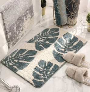 Detail of plush absorbent bath mat with blue monstera leaf pattern on marble floor