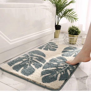 Detailed close-up of a plush anti-slip bath mat with blue monstera leaves on marble floor