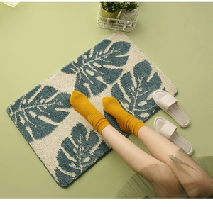 Detailed view of rectangle bath mat featuring Nordic monstera leaf pattern on green floor