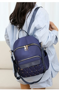 Detail view of navy oxford backpack with gold rivets and quilted texture on model