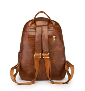 Detail view of the brown vintage leather backpack showing back zipper pocket and straps