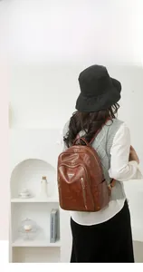 Brown vintage faux leather backpack with multiple zipper pockets shown on a female model