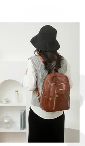 Close-up of vintage brown leather backpack with multiple gold zippers and stylish pockets