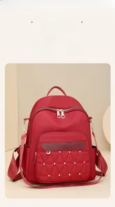 Close-up of red oxford fabric backpack featuring diamond quilting and gold rivets