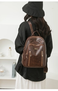 Detail view of deep brown vintage leather backpack with golden zippers and smooth texture
