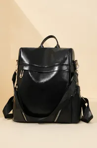 Close-up of minimalist black leather backpack with gold zippers and side pocket detail