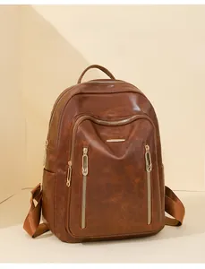 Detail view of brown faux leather backpack with multiple gold zippers and soft grain texture
