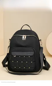Detail of black quilted nylon backpack with gold studs and high-density texture