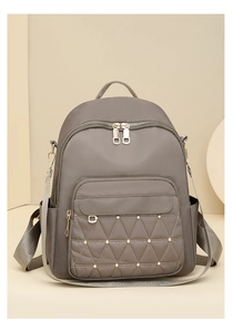 Detail view of the gray-coffee nylon backpack with quilted front pocket and gold studs