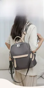 Detailed back view of a person wearing the grey nylon backpack with beige leather handles